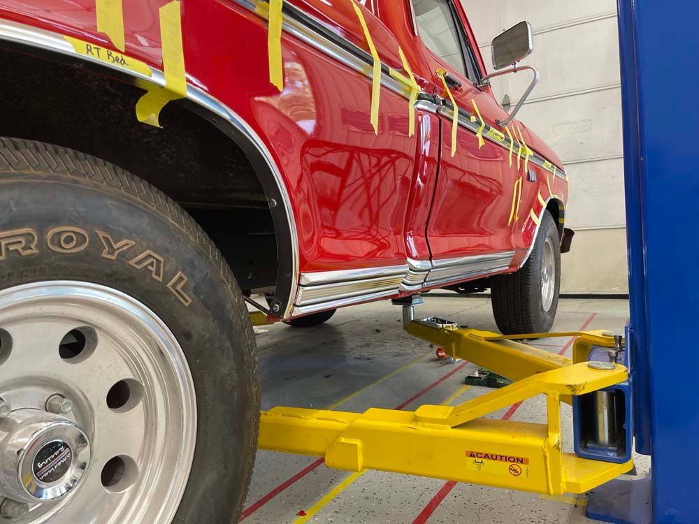 A red truck is on a lift with a royal tire