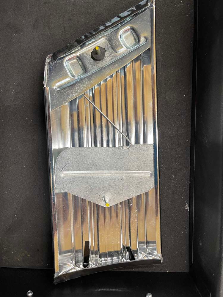 A metal object is sitting on a black surface.