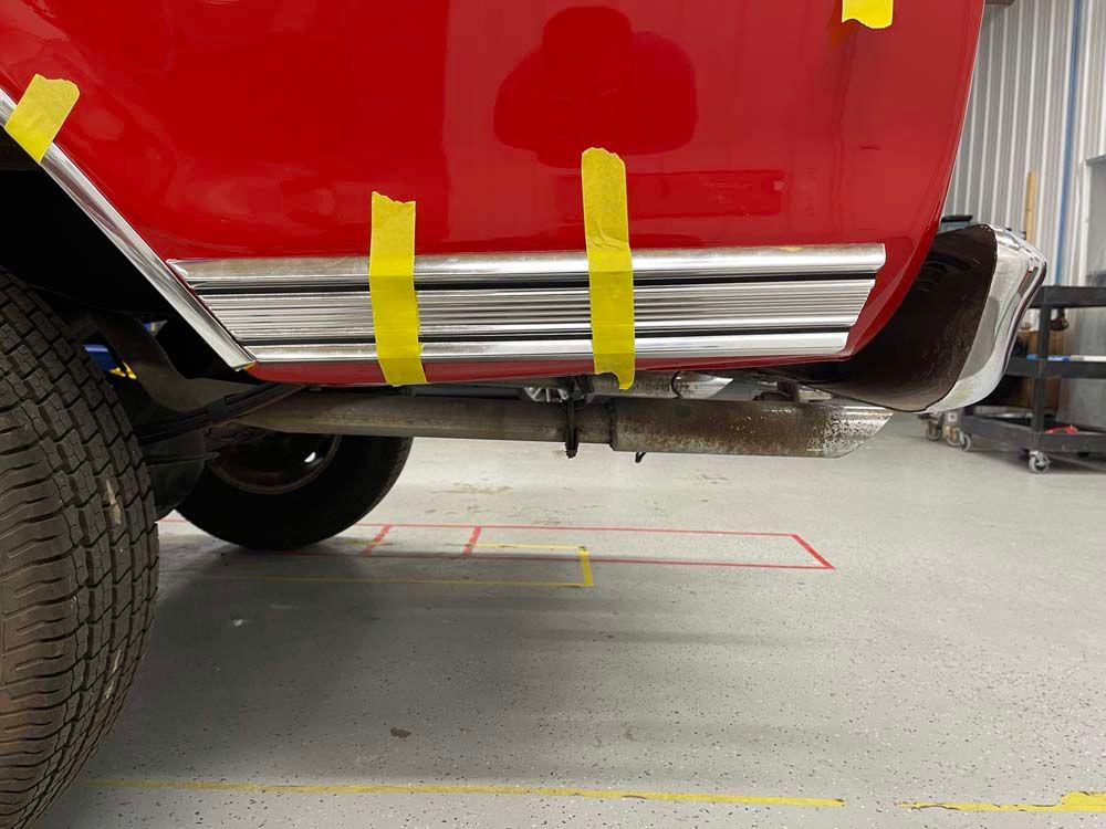 A red car with yellow tape on it is sitting in a garage.