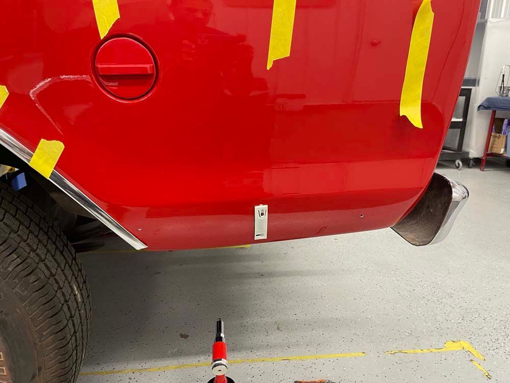 A red truck with yellow tape on it is parked in a garage.
