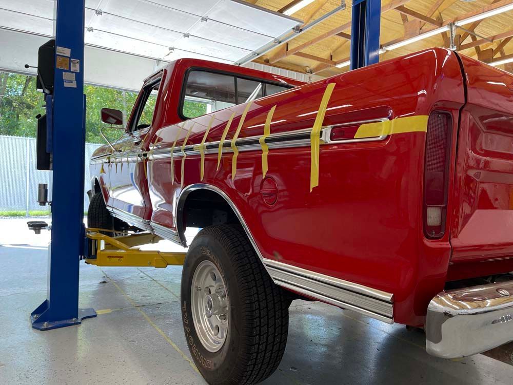 A red truck is sitting on a lift in a garage.