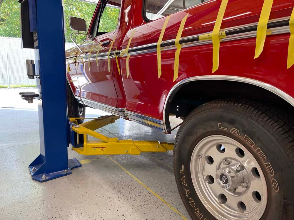 A red truck is sitting on a lift in a garage.