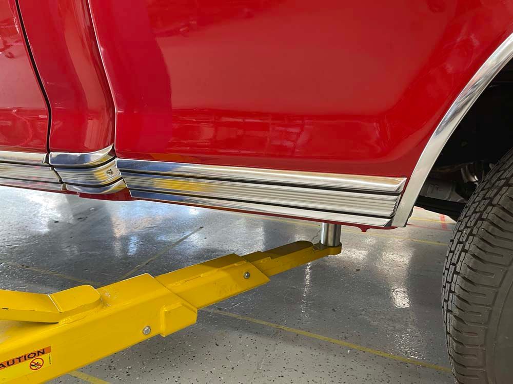 A red car is sitting on a yellow lift in a garage.