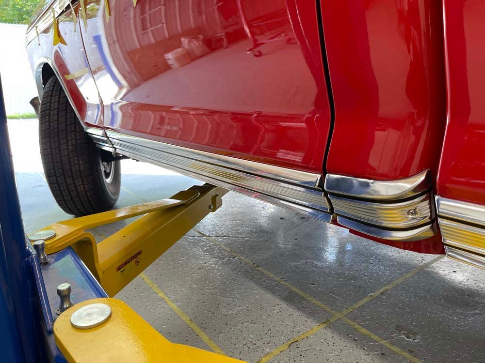A red truck is sitting on a yellow lift in a garage.
