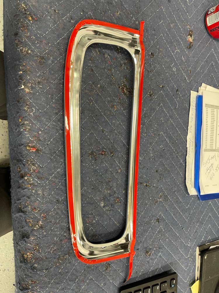 A piece of chrome with a red trim is sitting on a blue blanket.