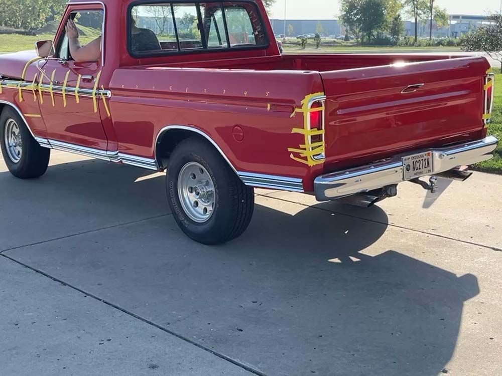 A red pickup truck is parked on a concrete driveway