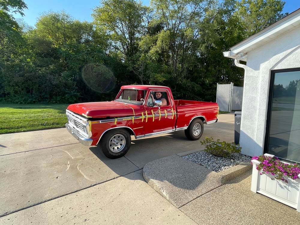 A red truck is parked in front of a white house.