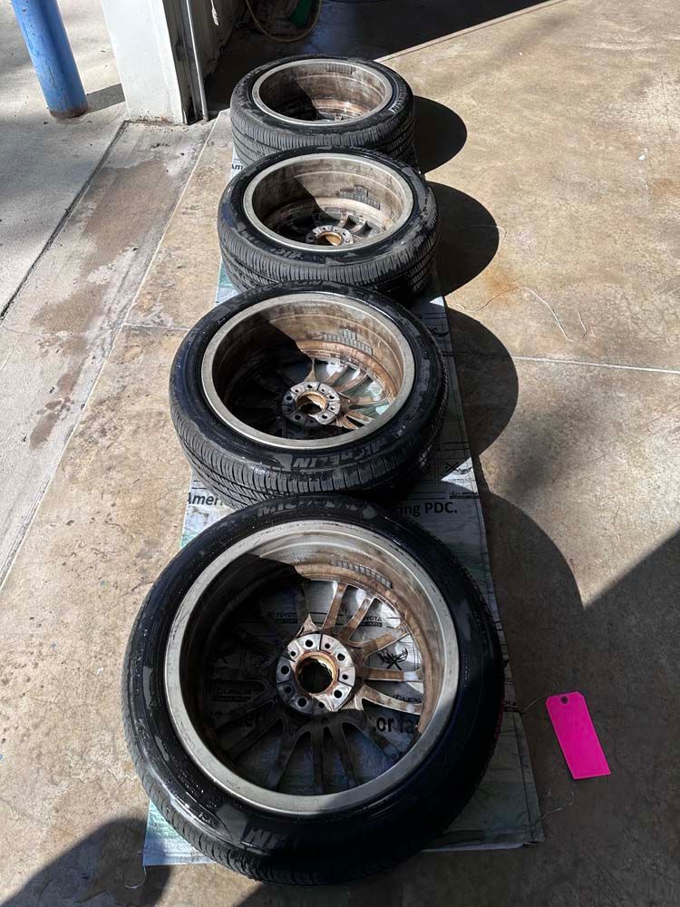 A row of tires and wheels are lined up on a concrete surface.