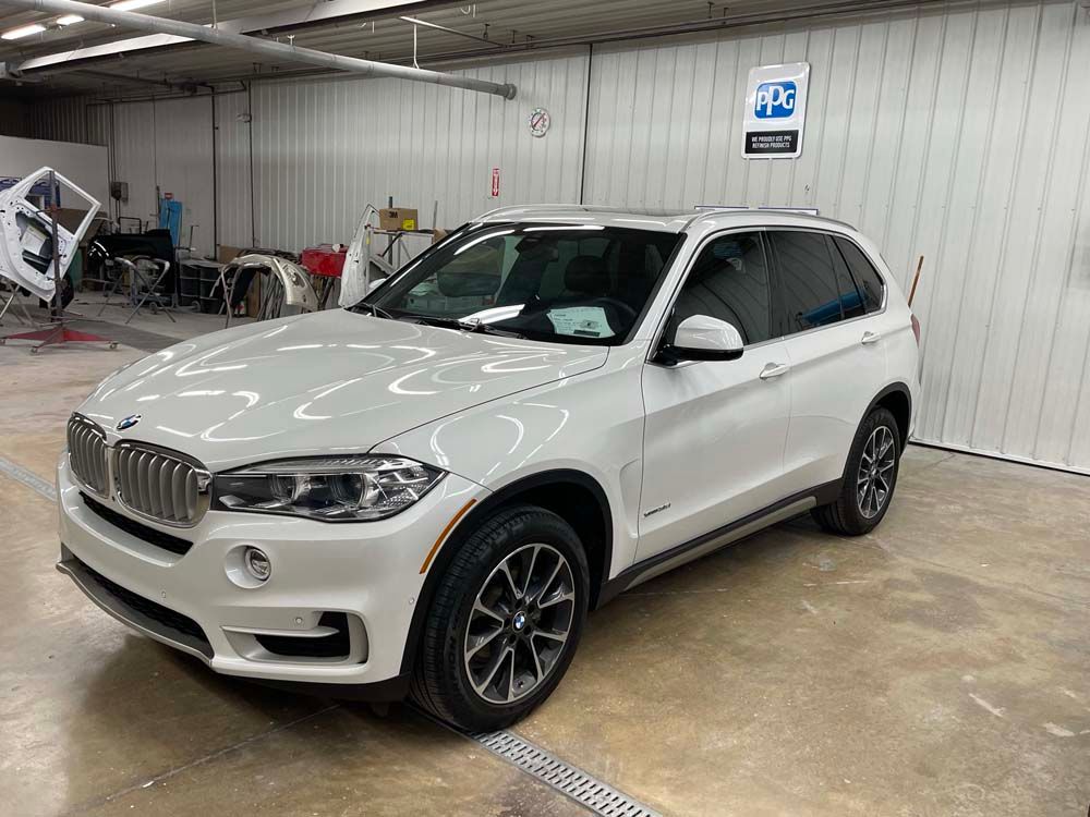 A white bmw x5 is parked in a garage.