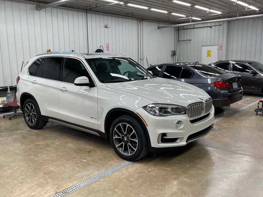 White BMW SUV parked inside a garage with tinted windows.