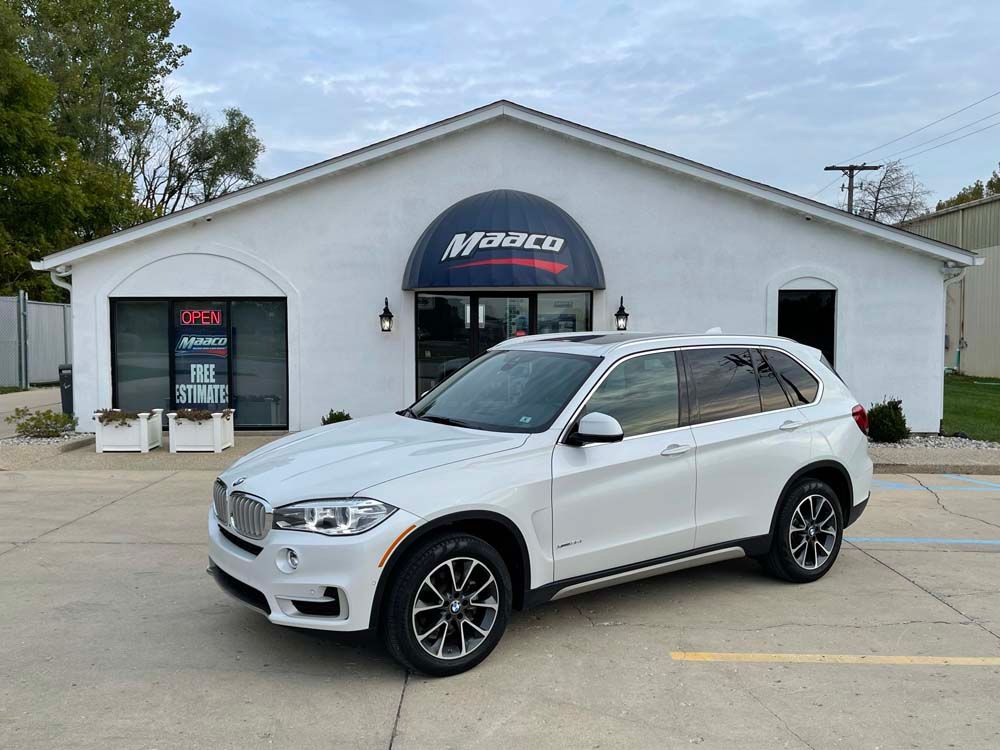 A white bmw x5 is parked in front of a white building.