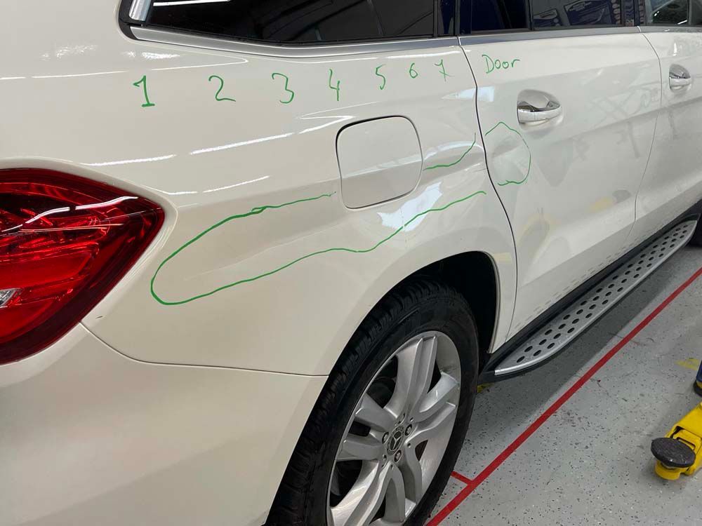 A white car with a green line drawn on the side of it.