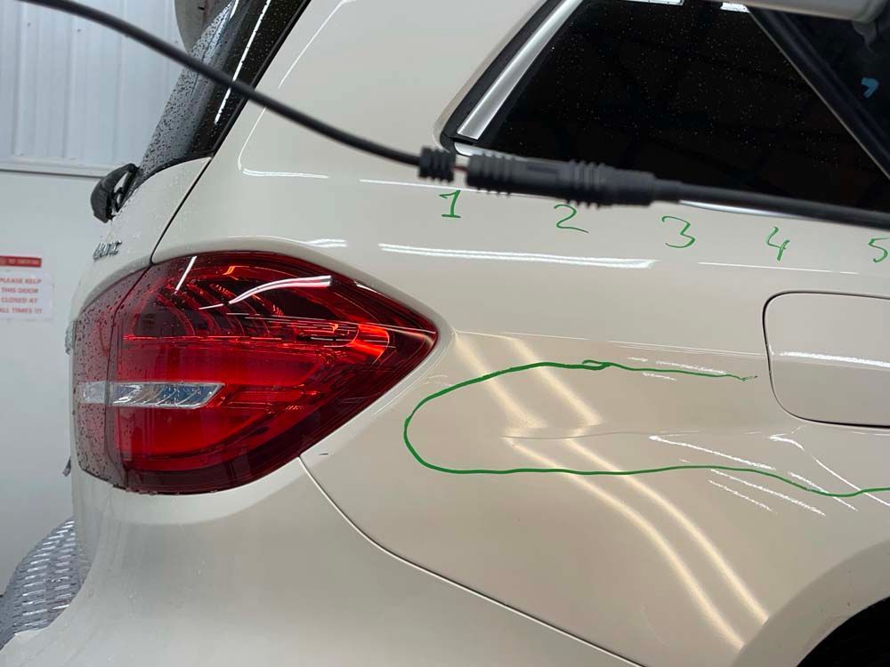 A white car with a green line drawn on it.
