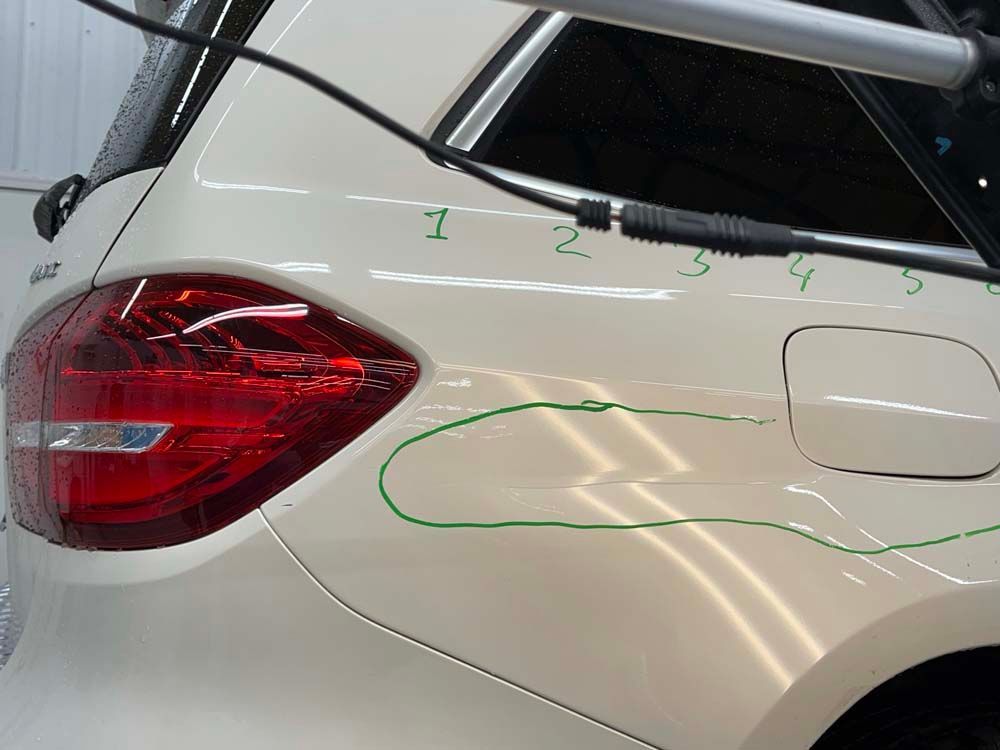 A white car with a green line drawn on it