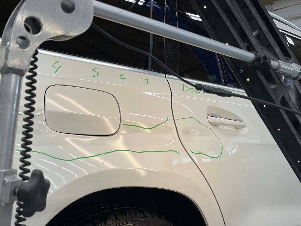 A white car is being examined by a machine with numbers written on it