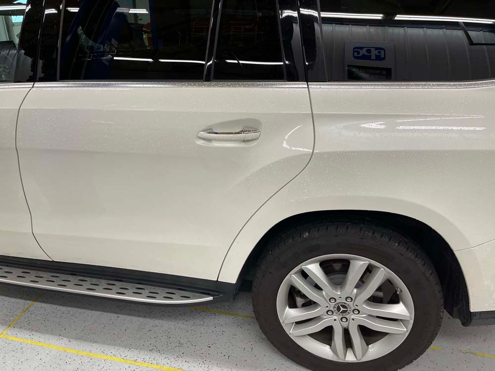 A white suv is parked in a garage with the door open.