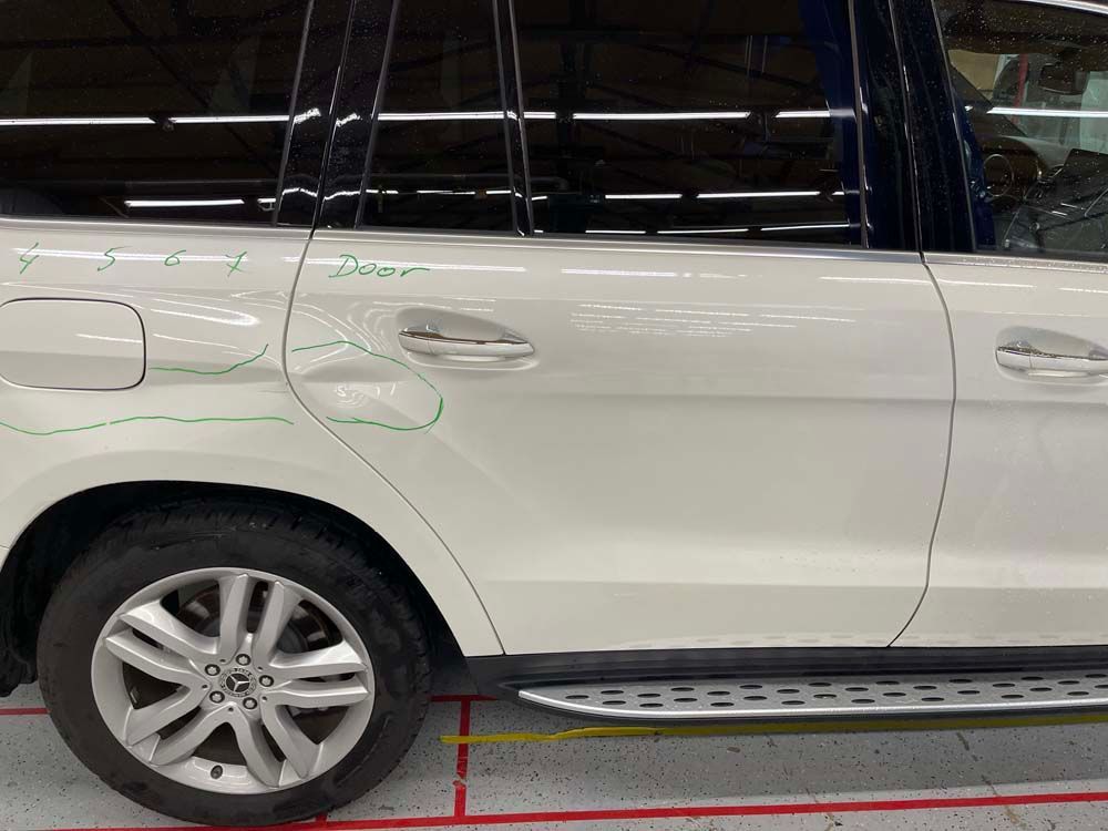 A white suv is parked in a garage with the door open.