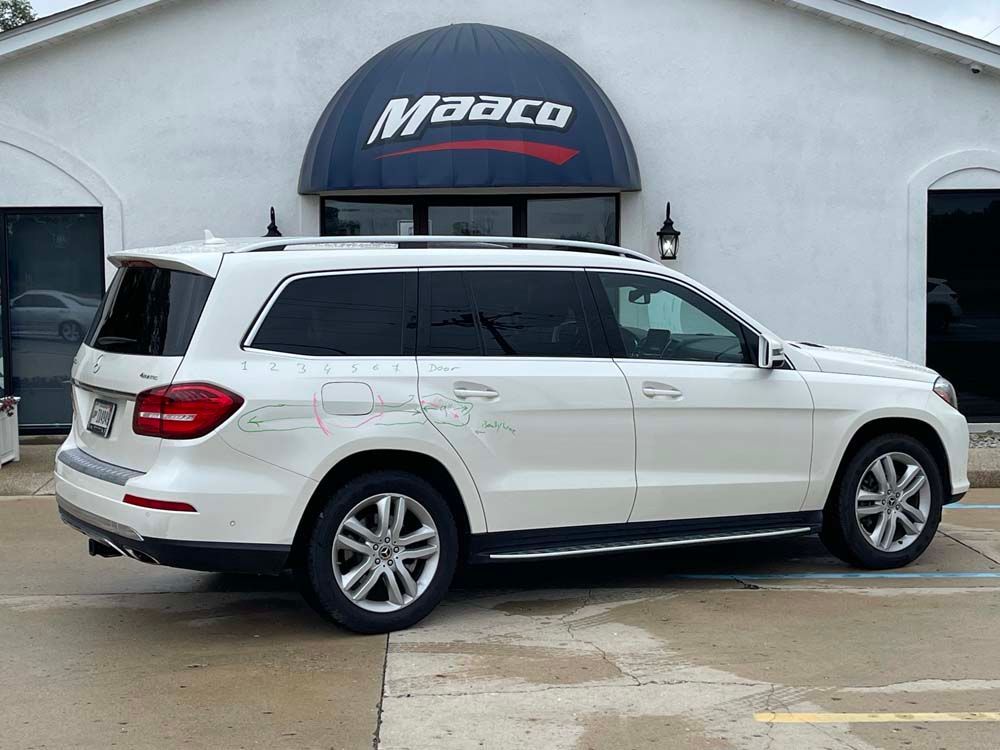A white mercedes benz gl 550 is parked in front of a building.