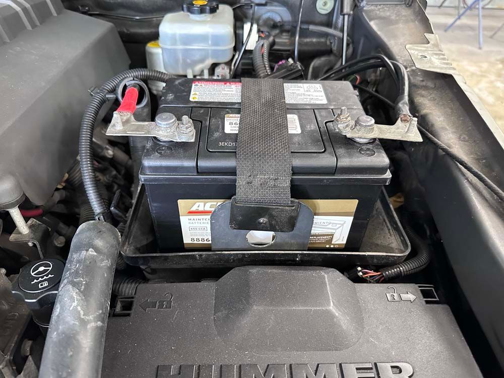 A battery is sitting under the hood of a hummer.