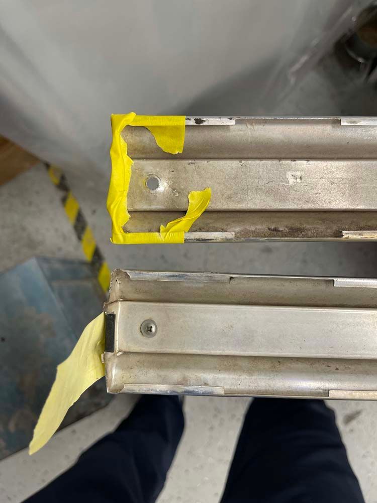 A person is standing next to a piece of metal with yellow tape on it.