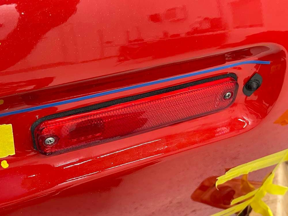 A red car with a yellow sticker on the back bumper.