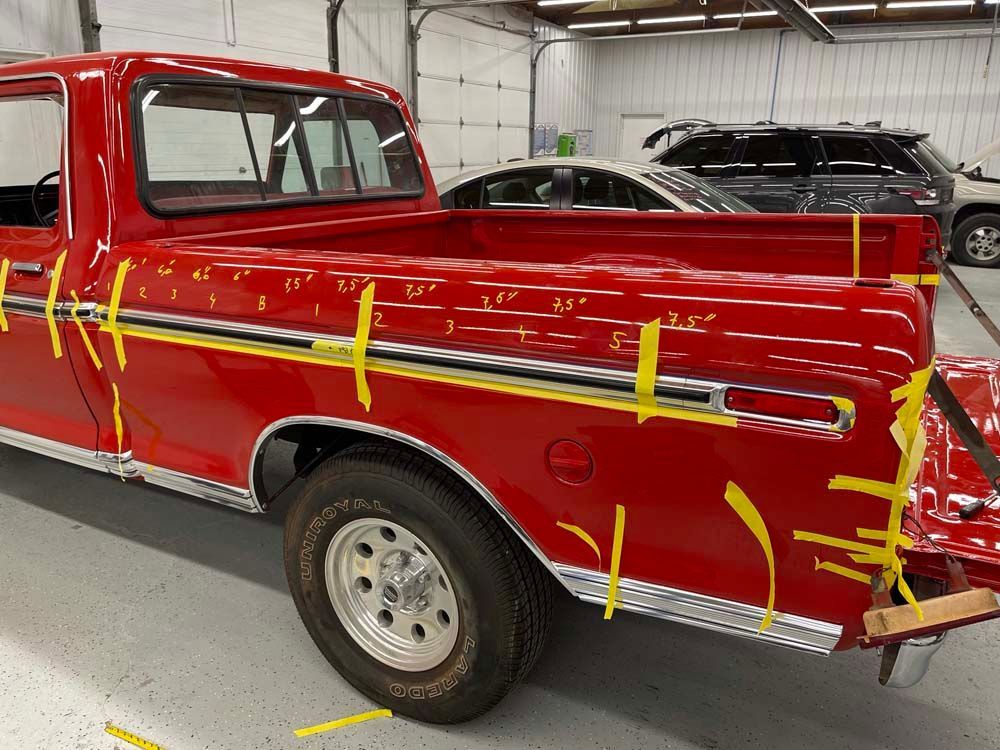 A red truck is taped to a wall in a garage