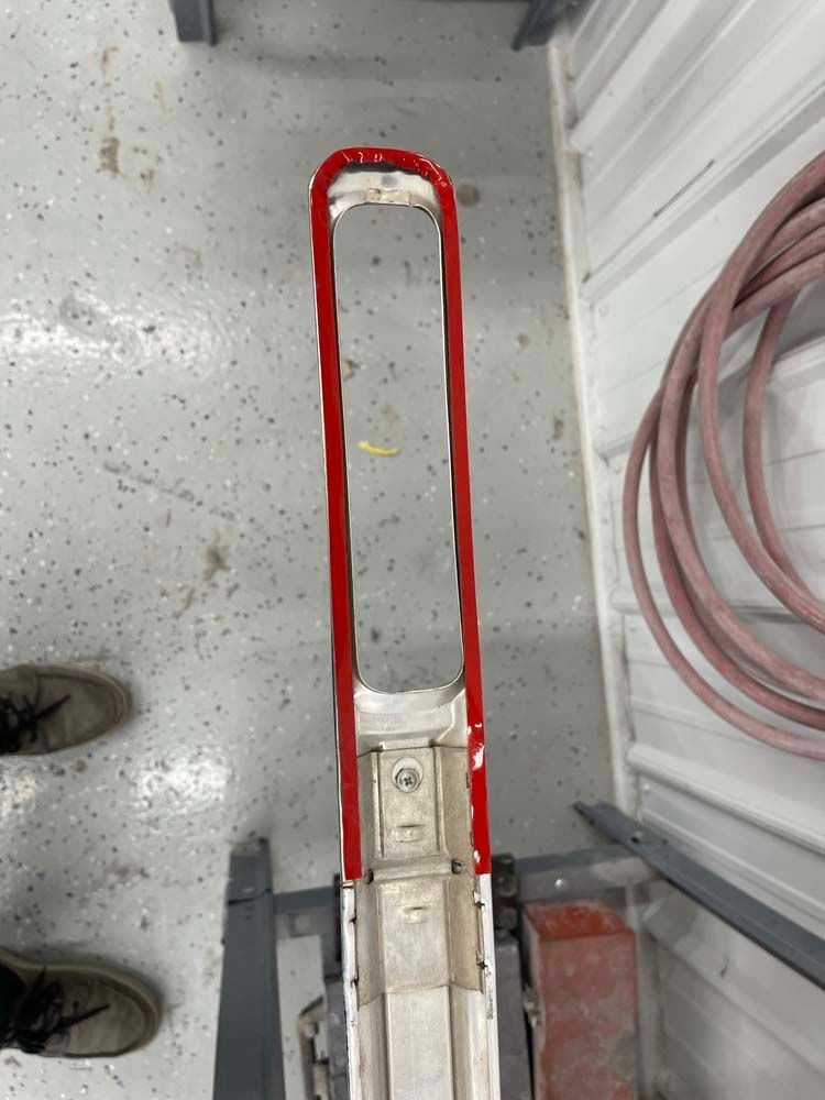 A red and white ladder is sitting on the floor in a garage.