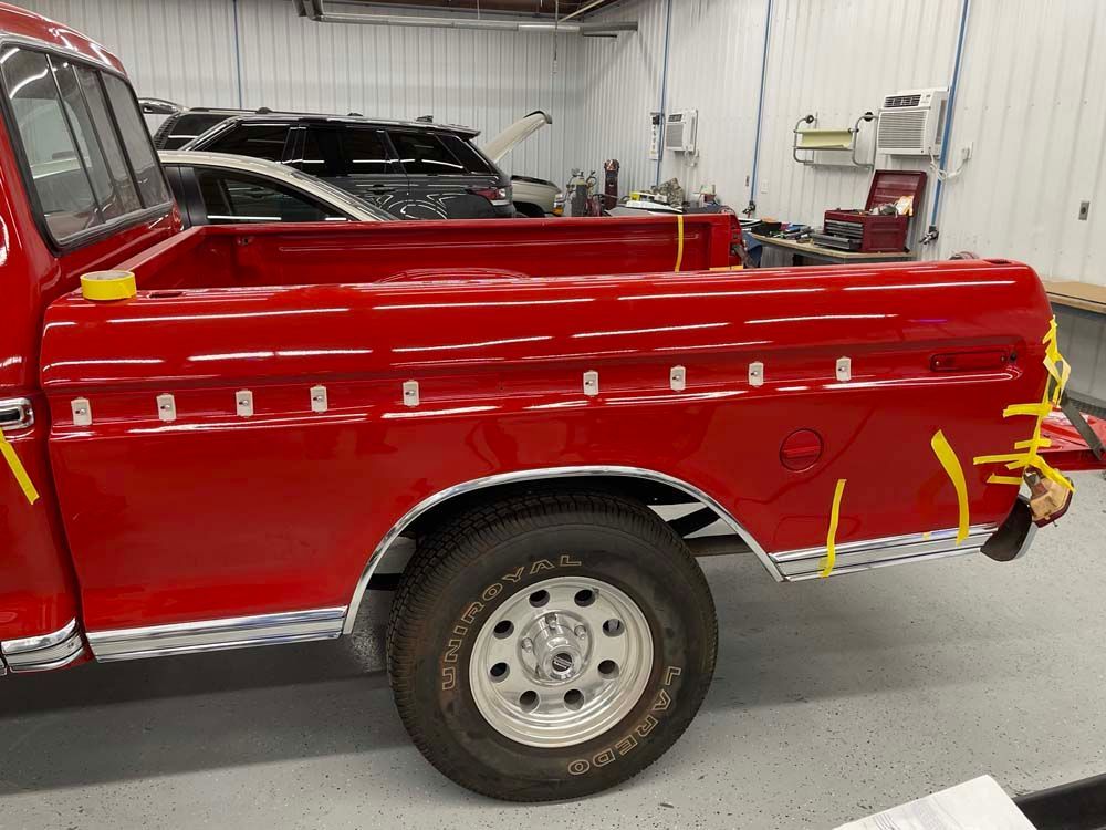 A red truck is parked in a garage with yellow tape on the side.