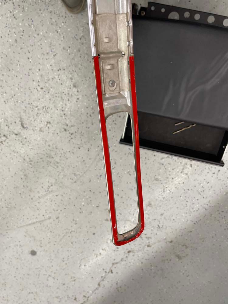 A piece of metal with a red trim is sitting on a concrete floor.