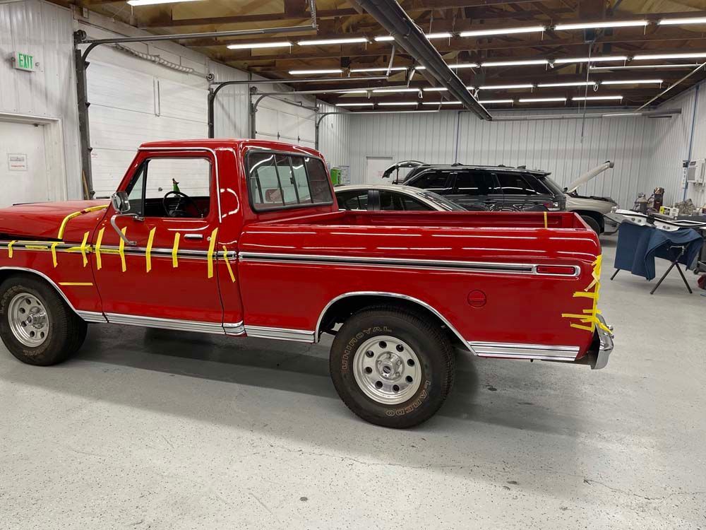 A red truck is parked in a garage with yellow tape on it.