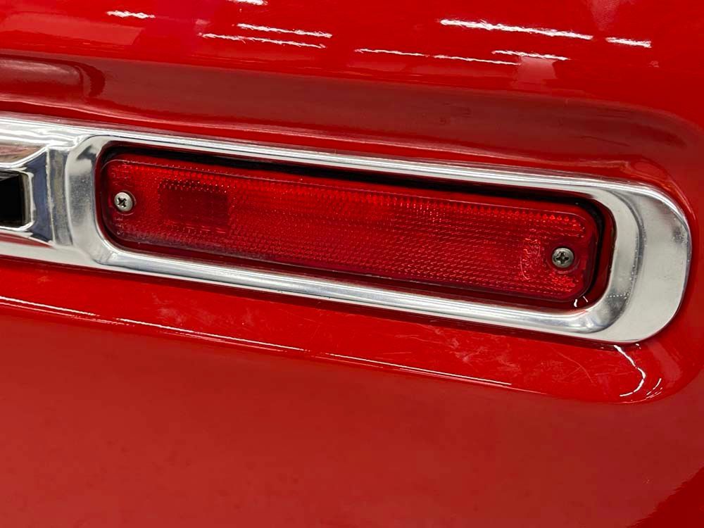 A close up of a red car 's tail light with chrome trim.