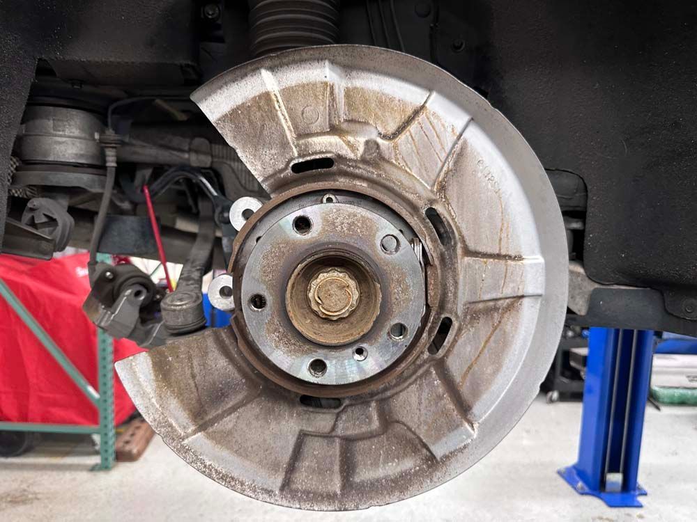 A close up of a brake disc on a car on a lift.