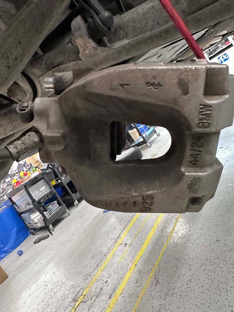 A close up of a brake caliper on a car in a garage.