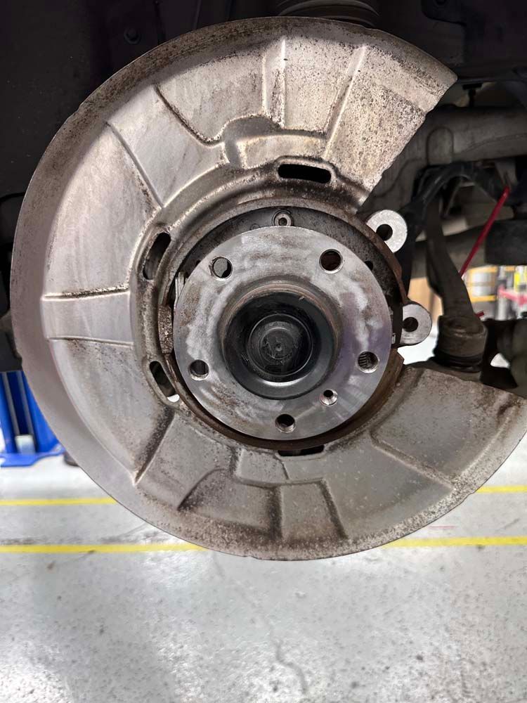A close up of a brake disc on a car in a garage.