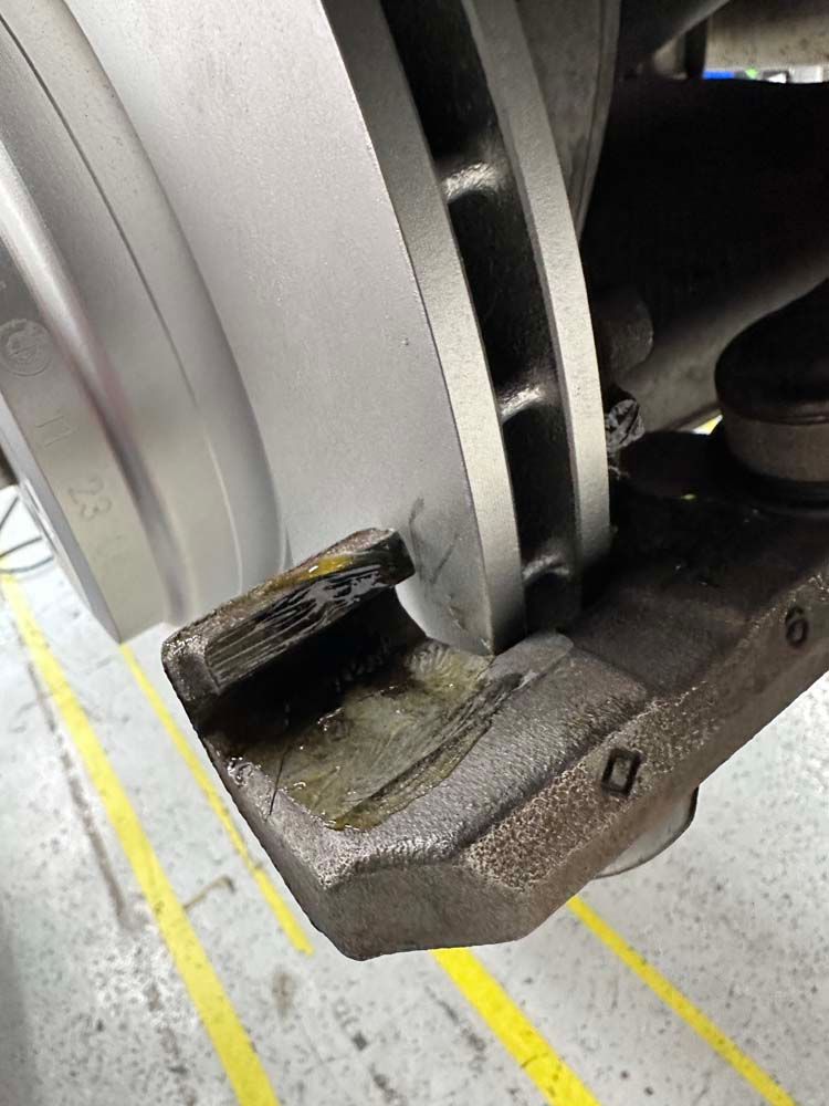 A close up of a brake disc on a car in a garage.