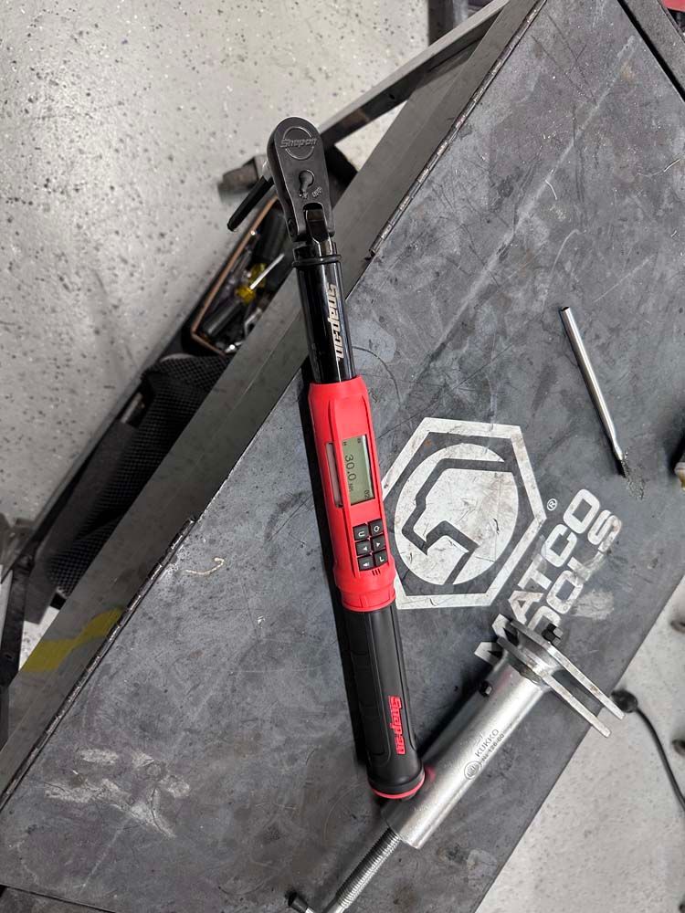 A digital torque wrench is sitting on top of a black table.