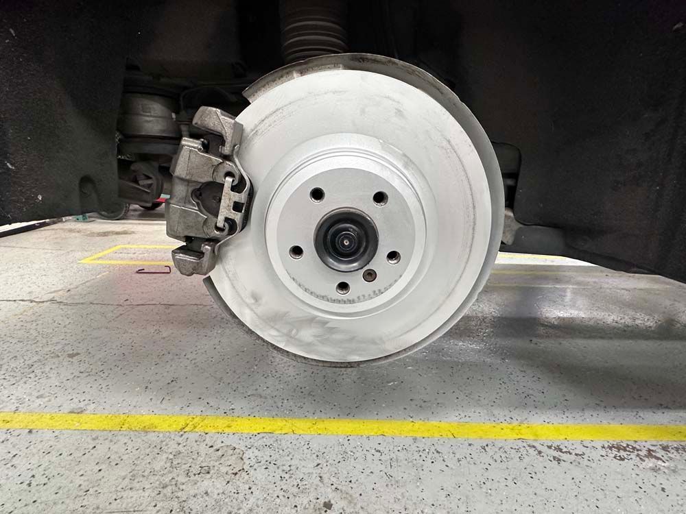 A close up of a brake disc on a car in a garage.