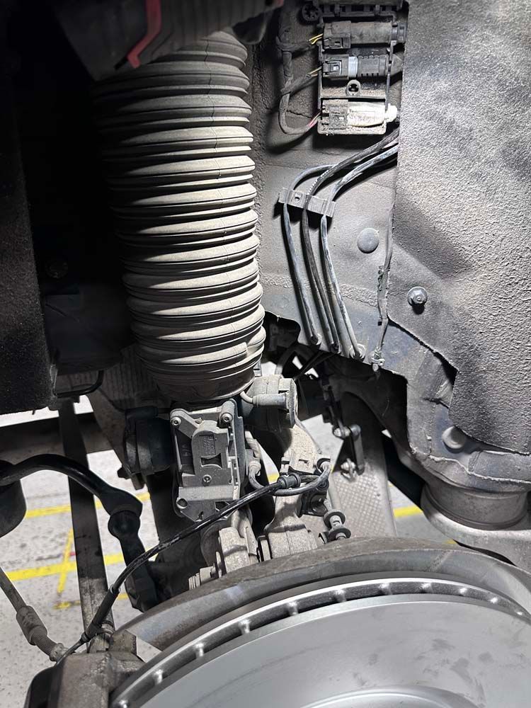 A close up of a car 's suspension and brake disc.