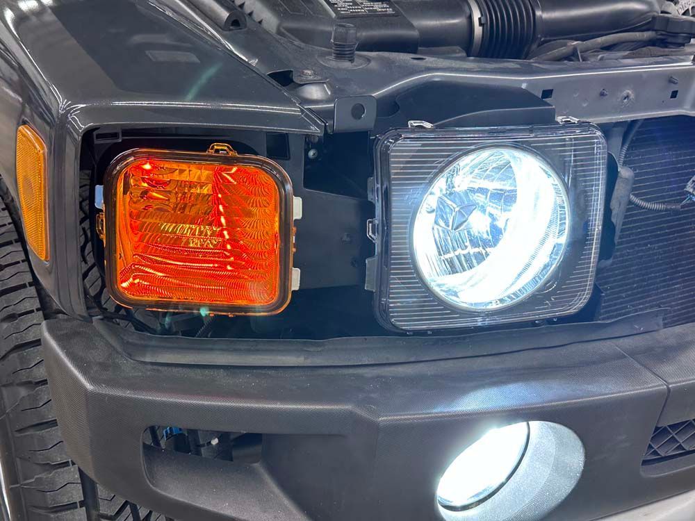 A close up of a car 's headlights with the hood open.