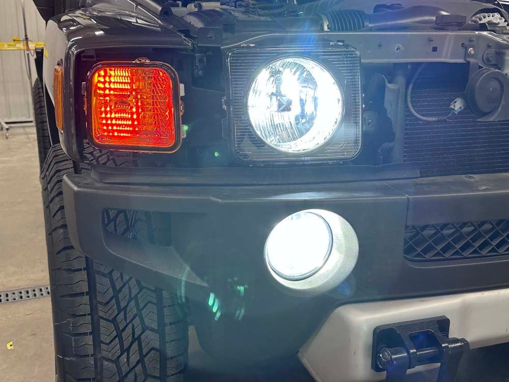 The front of a hummer h3 with the hood open and the headlights on.