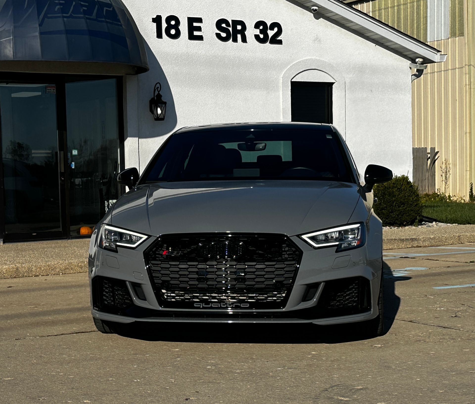 Gray Audi RS3 parked in front of a building with 