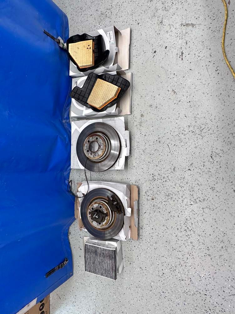 A bunch of brake pads are sitting on the floor next to a blue tarp.