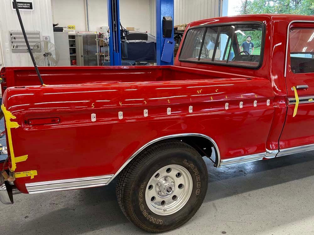A red truck is parked in a garage with yellow tape on it