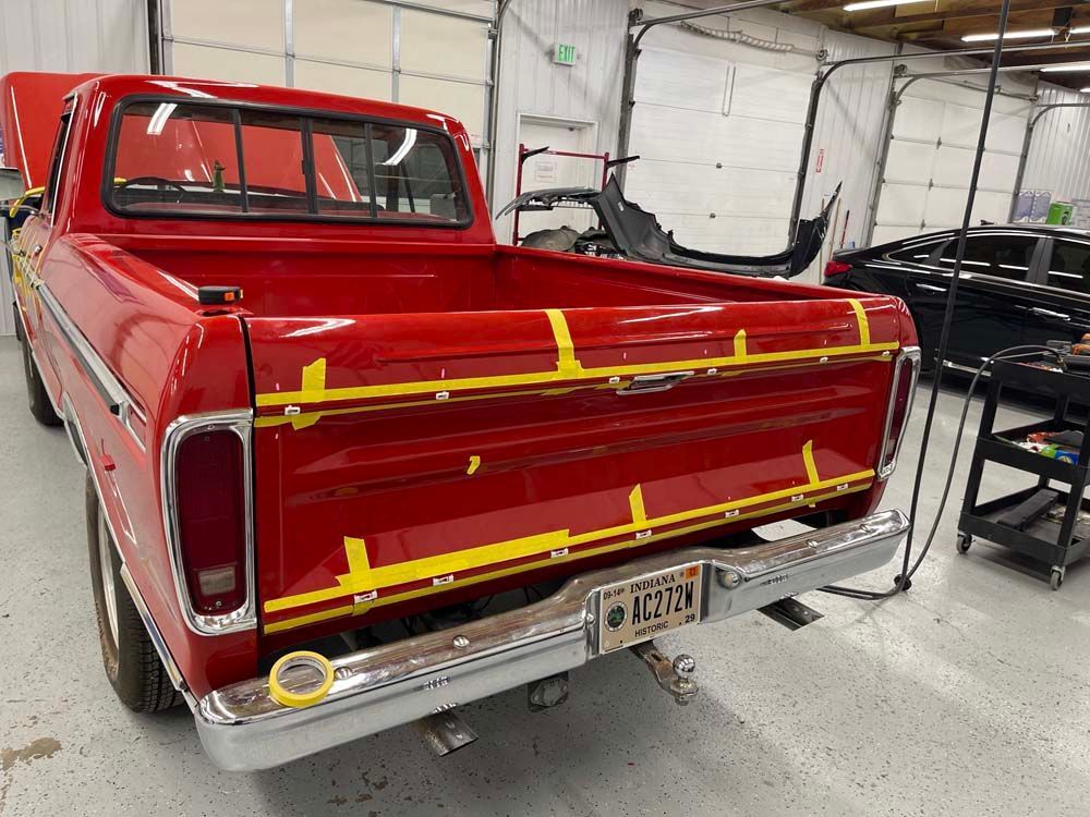 A red truck is being worked on in a garage.