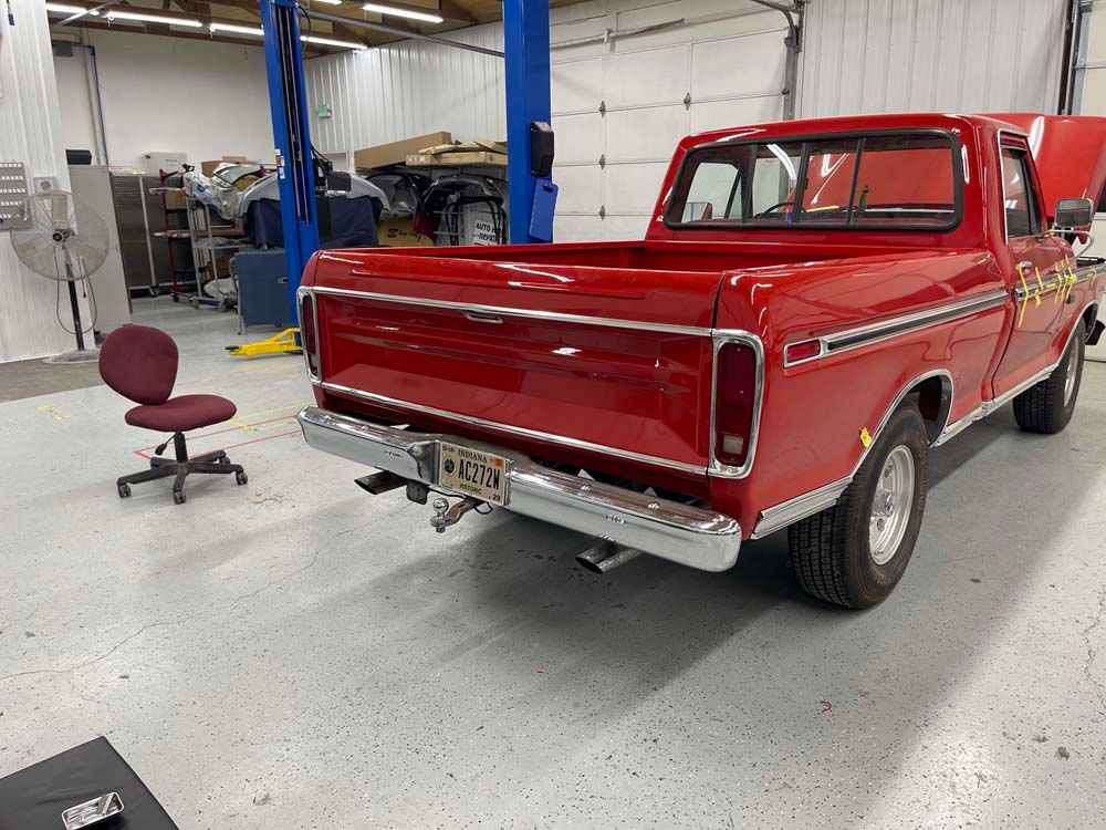 A red truck is parked in a garage next to a chair.