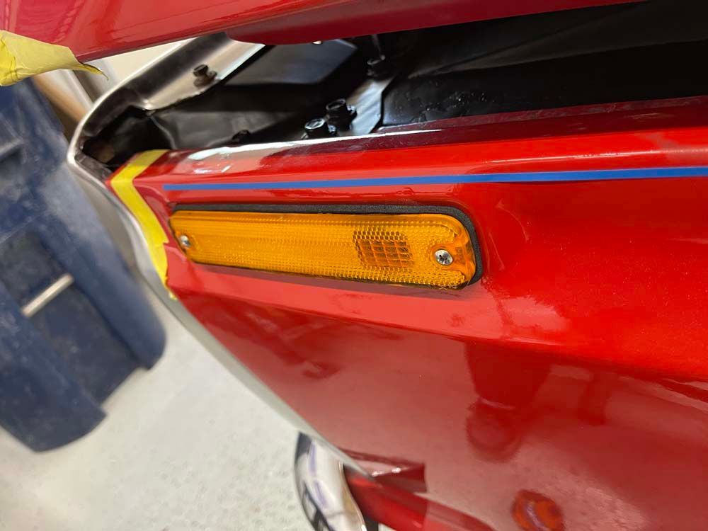 A close up of a red car with a yellow light on the side.