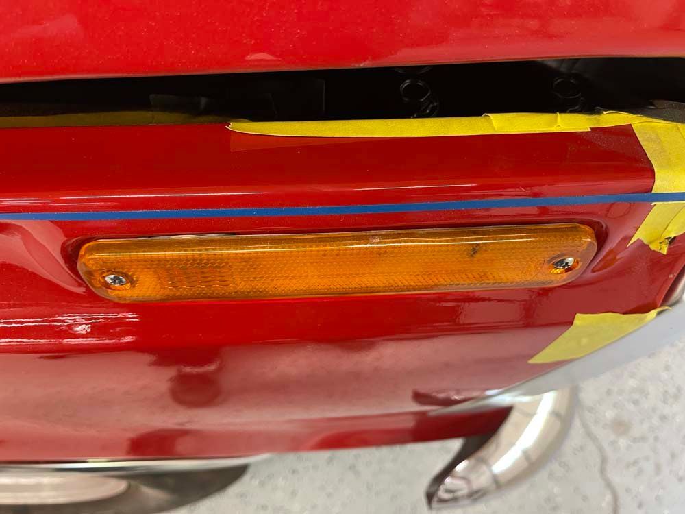 A close up of a red car with yellow tape on it.