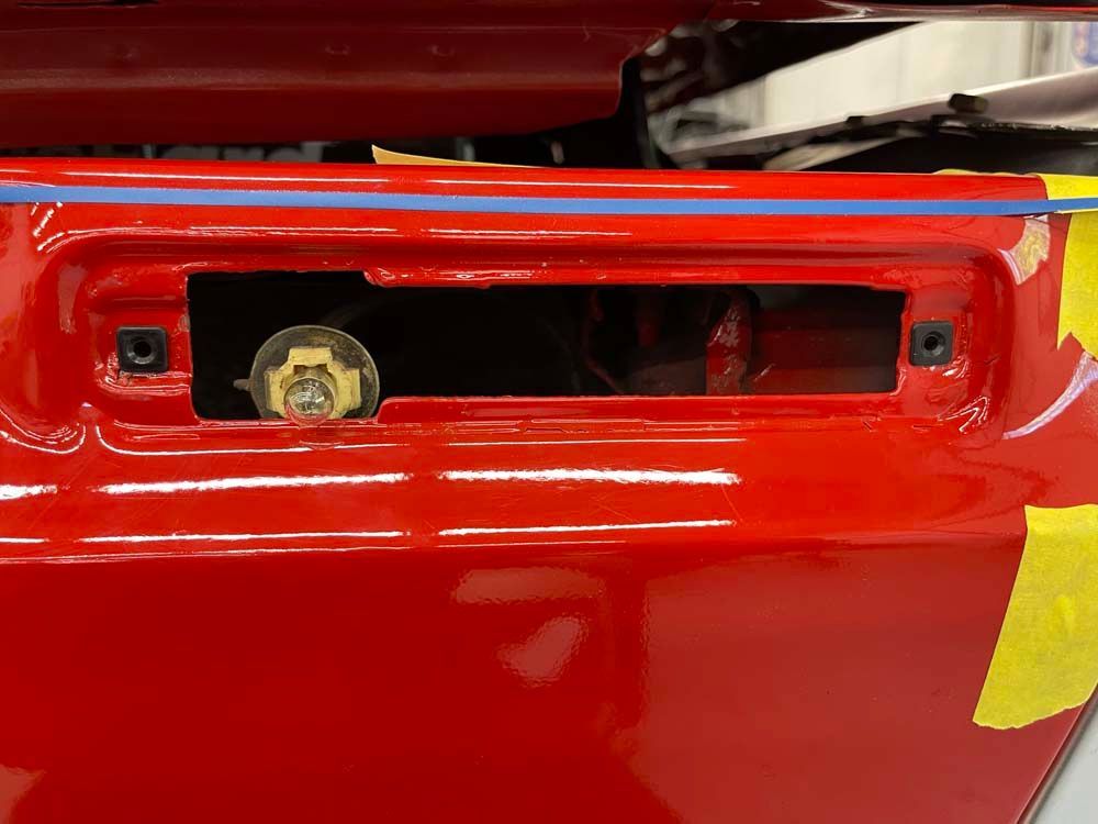 A close up of a red car with a yellow tape on it.