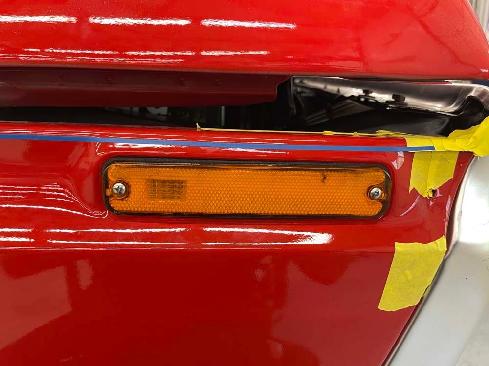 A close up of a red car with yellow tape on it.