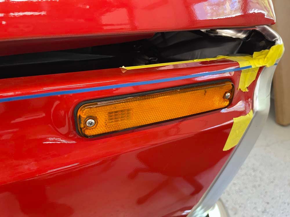 A close up of a red car with yellow tape on it.